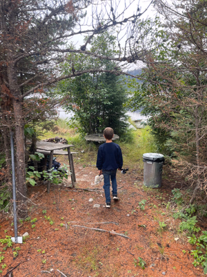 Entrance to lake shoreline with garbage can, table, and other items left behind.